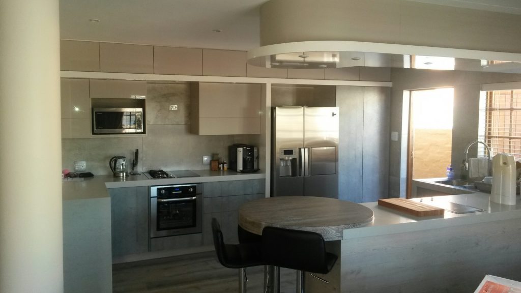 Handleless kitchen in Seno HiGloss Cashmere, Hemlock Nordique Kaindl and London Grey Caesarstone