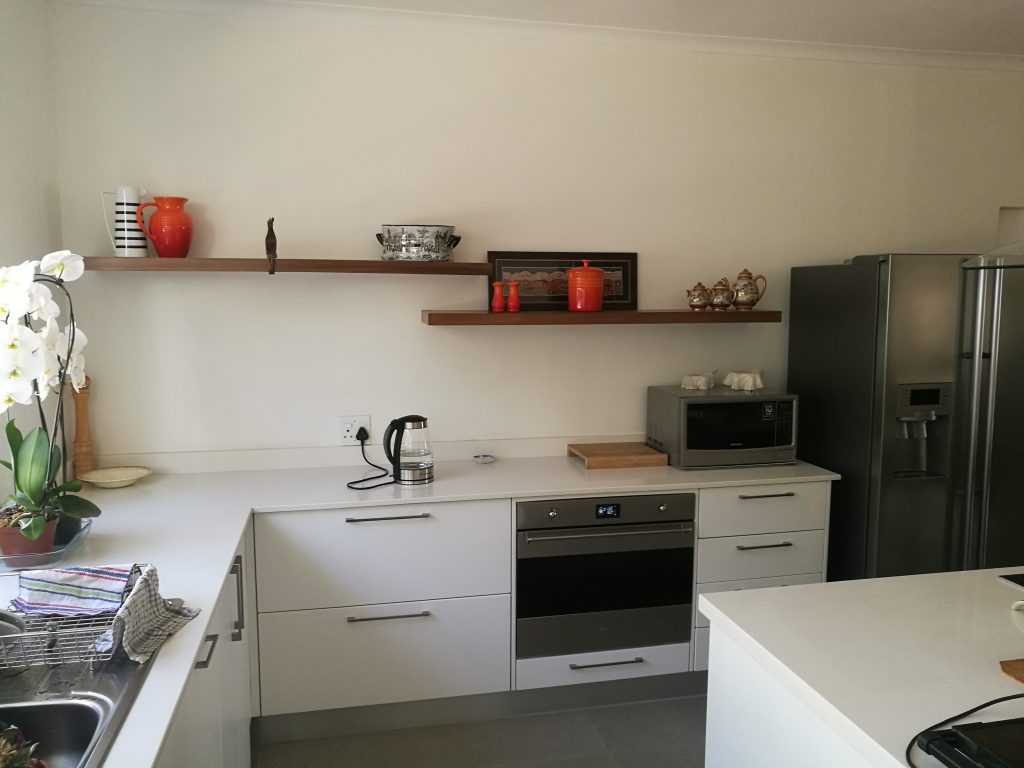 Wrap doors in Satin White, worktops in Sorbet Quartz and floating shelves in Walnut veneer