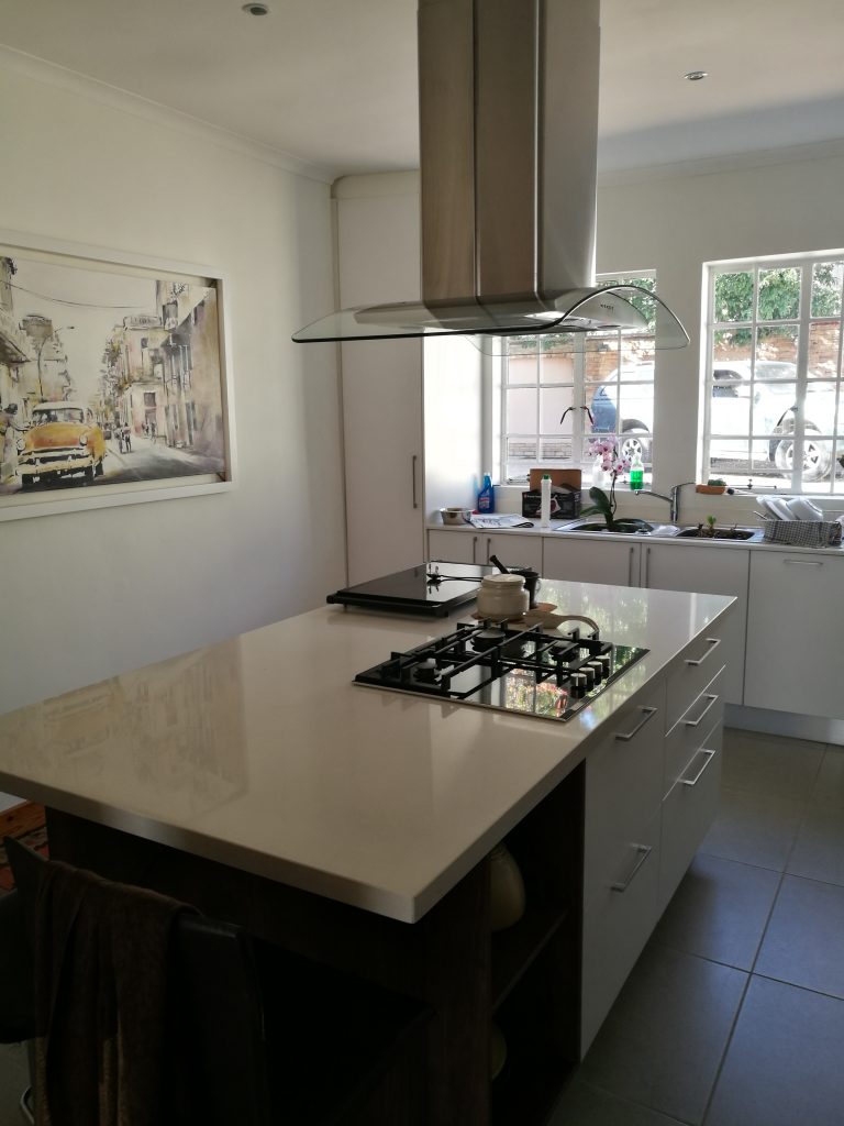 Wrap doors in Satin White, worktops in Sorbet Quartz and floating shelves in Walnut veneer