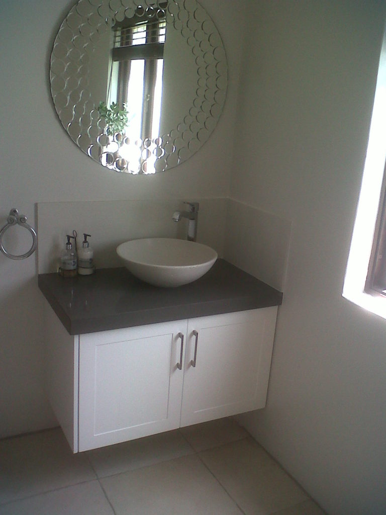 Floating vanity with sprayed shaker doors and a thick Storm Quartz top